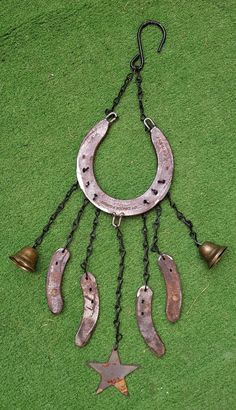 an old metal chain with bells hanging from it's sides on the grass in front of a green wall