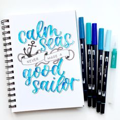 a notebook with some markers next to it and an ink pen on the cover that says calm seas never made good sailor