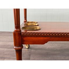 a wooden table with two brass plates on it's top and one gold plate on the bottom