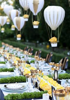 a long table is set with plates and hot air balloons in the shape of lanterns