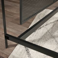 a close up of a metal frame on a wooden floor with a rug underneath it