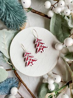 two red and white christmas trees are sitting on top of the table next to berries