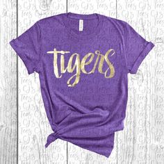 Soft comfy t-shirt and tank with gold foil lettering. Perfect for LSU events! T-Shirts are unisex fit and true to size. Tanks are fitted and true to size. Size up for looser fit. NOTE: When laundering, please do not use fabric softener and wash inside out if possible. Fabric softener and other additives can cause the foil to break down and will likely render the shirt unwearable. Please reach out to me with any questions. Lsu Shirts Vinyl Women, Gold Crew Neck T-shirt With Letter Print, Gold Crew Neck Top With Screen Print, Gold Short Sleeve Top With Text Print, Gold Short Sleeve T-shirt With Text Print, Gold Casual T-shirt With Letter Print, Gold Graphic Tee With Letter Print, Casual Gold T-shirt With Screen Print, Gold Casual T-shirt With Screen Print