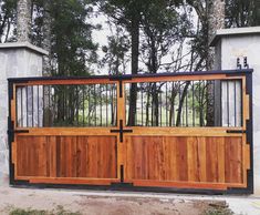 a wooden gate with metal bars on it and trees in the backgrouds