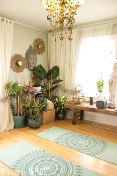 a living room filled with lots of plants next to a chandelier and window