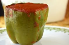 a green pepper covered in red stuff on a white plate