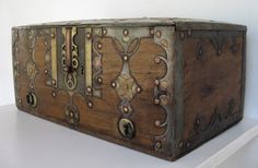 an old wooden box with ornate designs on it's sides and handles, sitting on a shelf