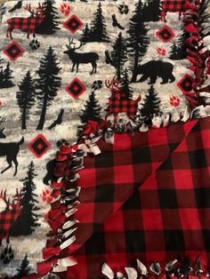 a red and black plaid blanket with moose, trees and snowflakes on it