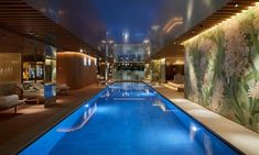 a large indoor swimming pool with blue water and flowers on the wall next to it