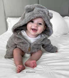 a baby in a bear costume sitting on a bed