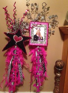 two pink and black decorations hanging on the wall next to a mirror with a picture frame