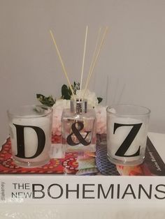 two candles are sitting on top of a book with the letters d and z painted on it