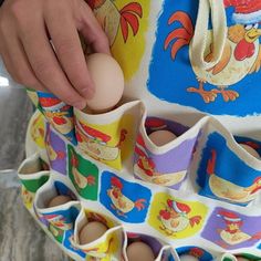 a person holding an egg in front of some eggs on a rack with chicken designs