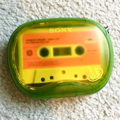 an orange and green cassette player on the floor next to a white carpeted area