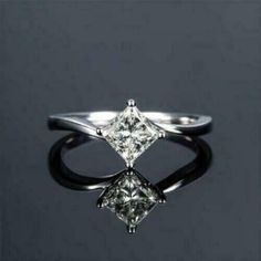 a white gold ring with a princess cut diamond set in the center, on a black background