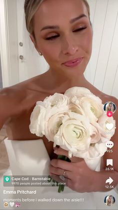 a woman in a wedding dress holding a bouquet of white flowers and looking at the camera