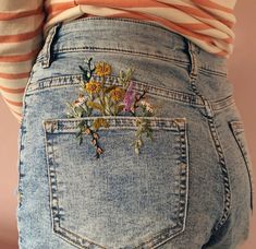 the back of a woman's jean pants with flowers on it and an orange striped shirt