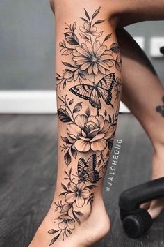 a woman's leg with flowers and butterflies on it, while she has her legs tattooed