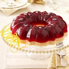 a jelly cake on a glass plate with gold trimmings and decorations around it