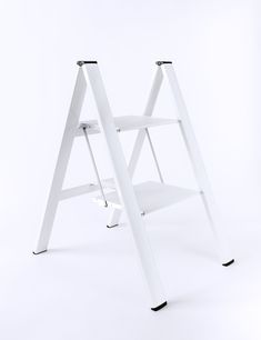 two white step stools sitting next to each other on a white surface with black feet