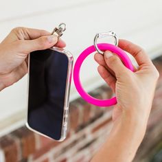 a person holding a cell phone with a pink ring around it