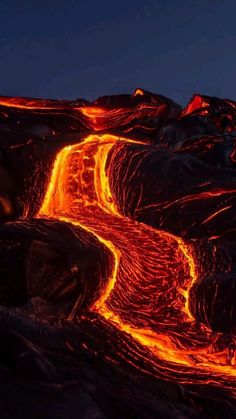 an image of lava flowing down the side of a mountain at night with bright orange lights