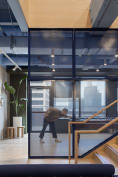 a person walking up the stairs in an office with glass walls and steel railings