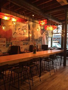 an empty restaurant with wooden tables and bar stools in front of large windows that look out onto the street