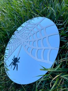 a blue frisbee sitting in the grass with a spider on it's side