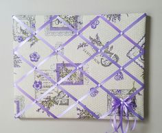 a purple ribbon tied to a white and blue patterned paper with lavender flowers on it