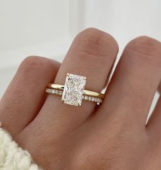 a woman's hand with a diamond ring on top of her finger and an engagement band