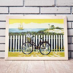 a painting of a bicycle with flowers in the basket is displayed on a wooden table