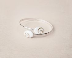 Our 925 Sterling silver delicate bracelet is perfect for elegant ocasions. This unique design consists in two stones of Santa Lucia 14 mm in oval shape, a natural shell also know as Shiva Eye Shell. The shiva shell is a natural fossil seashell. This piece is fully adjustable, able to wear it on the up side of the arm or on the wirst. This delicate bracelet is the a perfect present for all those who loves the sea and natural beauty. Details: - 925 Sterling Silver Stamp - Able for sensitive skins. Shiva Eye, Bracelet Stone, Lapis Lazuli Ring, Santa Lucia, Tiny Earrings, Shell Bracelet, Gift For Mum, Gem Ring, Blue Gems