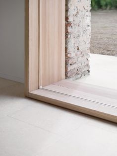 an open door with a brick wall and wooden frame in front of it, on the floor