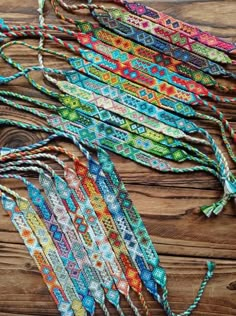 multicolored beaded bracelets are laid out on a wooden table with string