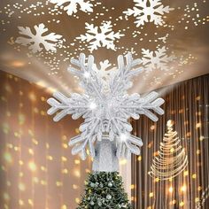 a christmas tree with snowflakes hanging from it's top in front of a window