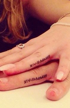 two people with matching tattoos on their fingers, one holding the other's hand