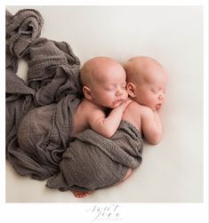 two newborn babies wrapped in grey blanket laying next to each other on top of one another