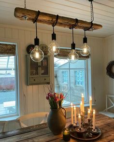 a wooden table topped with lots of lit candles next to a vase filled with flowers