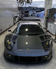 a black sports car parked in front of a gas station