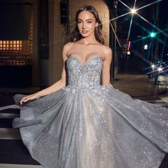 a woman in a silver dress is posing for the camera with her hand on her hip