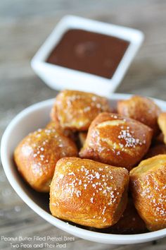 a bowl filled with pastries next to a cup of dipping sauce on top of a table