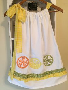 Lemonade Summer Party Dress with a lovely gingham yellow fabric bow on adjustable neckline, appliquéd lemons , limes and oranges on front and back. Green and yellow country ruffle just above hem. So cute for a lemonade theme birthday party or even your local summer lemonade stand This dress is a One of a kind and very versatile. Length of dress from gathered neckline to hem is 21 1/2 inches long. Armhole area is 5 inches long and of course the gingham yellow bow sets on shoulder. Full width at h White Cotton Easter Dress, Green Lemon Print Dress For Garden Party, Cotton Lemon Print Dress For Garden Party, Cute Yellow Dress For Picnic, Summer Cotton Dresses With Lemon Print, Yellow Cotton Dress For Picnic, Summer Cotton Dress With Lemon Print, Brunch Lemon Print Sundress, Cotton Lemon Print Sundress