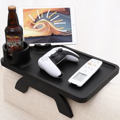 there is a tablet and two remotes on the table with beer, soda bottle, and game controller