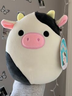 a stuffed cow with a tag on it's ear is hanging from a wall