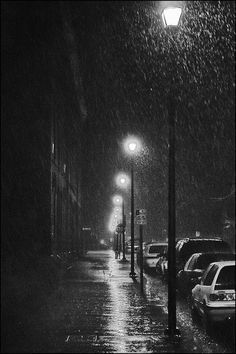 cars are parked on the side of the street in the rain as it is raining