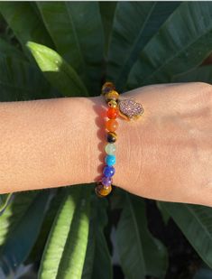 This is a beautiful bracelet with 7 chakra stones and a hamsa hand, made out of tiger's eye gemstone. The stones are known to help heal and balance one's chakras, and the hamsa is a symbol of protection. Perfect for anyone seeking inner peace and balance. Associated Chakras: 2nd (Sacral Chakra) or 3rd (Solar Plexus Chakra) Zodiac Signs: Virgo, Leo Elements: Air, Earth MANTRA: “I am motivated by my divine purpose and I manifest your vision with ease.” The Tiger's Eye crystal gets its healing prop Multicolor Natural Stones Spiritual Charm Bracelet, Spiritual Multicolor Charm Bracelet With Natural Stones, Adjustable Rainbow Stretch Bracelet, Spiritual Style, Adjustable Rainbow Spiritual Stretch Bracelet, Adjustable Rainbow Stretch Bracelet Spiritual, Spiritual Charm Bracelet With 8mm Beads For Healing, Spiritual Rainbow Beaded Bracelets, Spiritual Hand-strung Evil Eye Bracelet For Healing, Multicolor Spiritual Crystal Bracelet