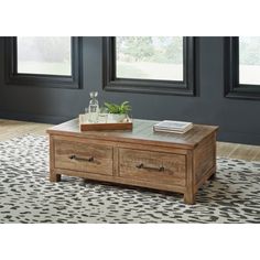 a wooden coffee table with two drawers and a plant on top in front of windows