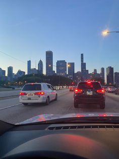 two police cars driving down the road in front of a cityscape at dusk