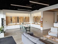 an empty room with furniture and glasses on display in the window cases, along with tables and chairs